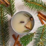 Bougie artisanale Belle Luce en cire de soja parfumée à la pomme et à la cannelle, vue de dessus. Décorée avec un bâton de cannelle et des herbes sur un fond en bois naturel, cette bougie évoque une ambiance chaleureuse et cosy, idéale pour l'hiver.